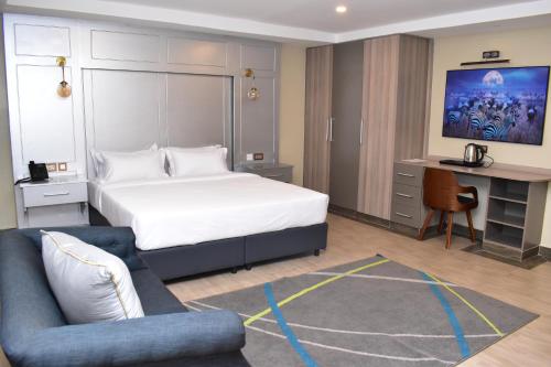 a bedroom with a bed and a desk and a couch at Dallas Premiere Hotel in Kisii