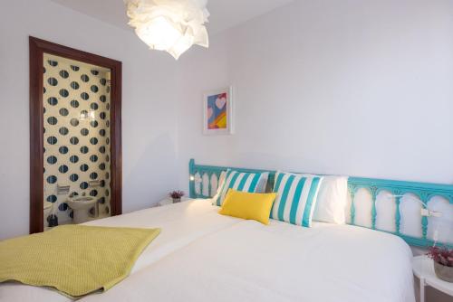 ein Schlafzimmer mit einem weißen Bett mit blauen und gelben Kissen in der Unterkunft MalagaSuite Pier Fuengirola in Fuengirola