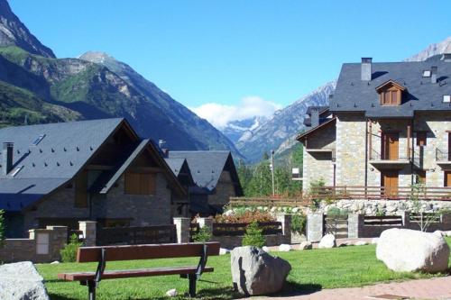 un banco de parque frente a un edificio con montañas en Apartamento Nevados 2620 en Anciles