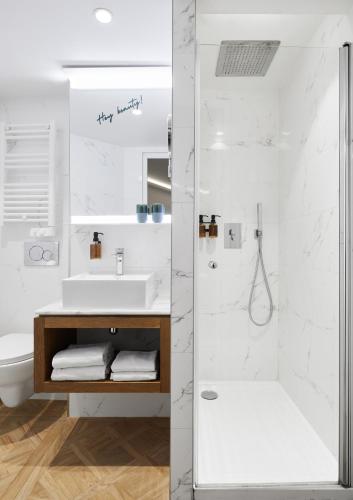 une salle de bain blanche avec un lavabo et une douche dans l'établissement Hotel Petit Lafayette, à Paris
