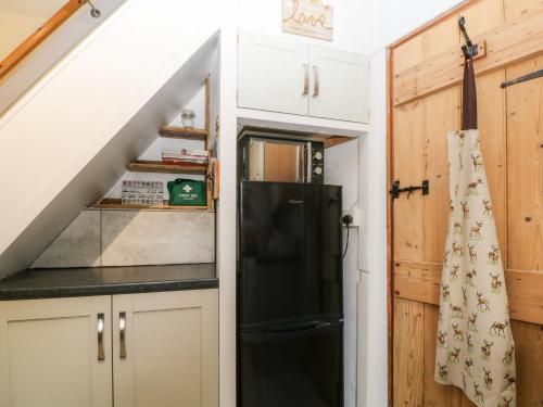eine Küche mit einem schwarzen Kühlschrank neben einer Treppe in der Unterkunft Vigo Cottage in Tavistock
