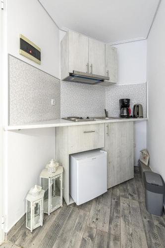 a kitchen with white cabinets and wooden floors at Comfort Stay Athens Airport Hotel - FREE shuttle from and to the airport in Spáta