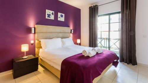 a bedroom with a bed with a purple wall at Central Albufeira Great Location 