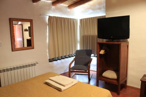 蒂爾卡拉的住宿－Hotel Punta Corral，一间卧室配有一张床、一台电视和一把椅子