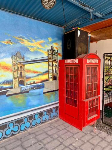 a red phone booth next to a wall with a painting at Little Rock Cebu in Mactan