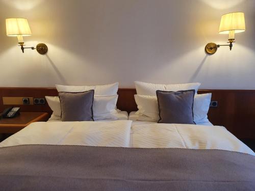 a bedroom with a bed with two lights on the wall at Käfernberg - Weinhotel in Alzenau in Unterfranken