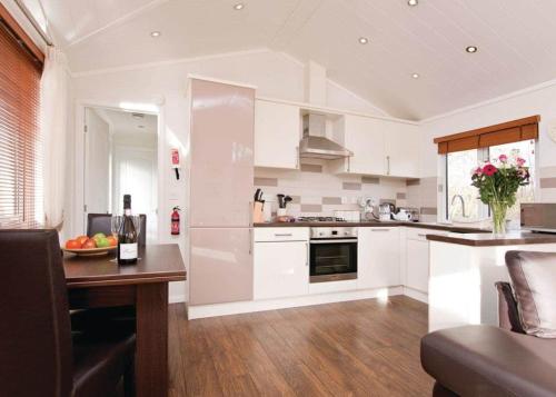 una cocina con armarios blancos y una mesa en una habitación en Herons Brook Retreat Lodges en Narberth