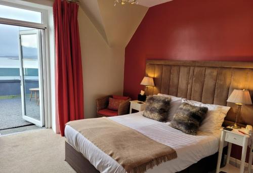 a bedroom with a large bed with a red wall at Loch Melfort Hotel in Ardfern