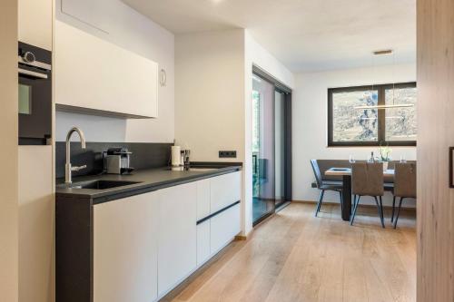 a kitchen with white cabinets and a dining room at Falsers Mountain Lodge in Cornedo all'Isarco