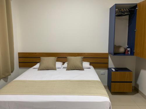 um quarto com uma cama branca e uma cabeceira em madeira em Studio Standard Comfort I AO LADO SHOPPING em Três Lagoas
