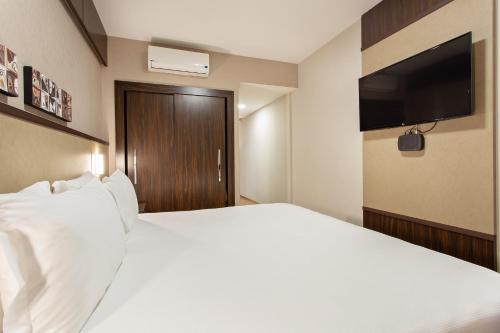 a hotel room with a white bed and a flat screen tv at Bourbon Londrina Hotel in Londrina