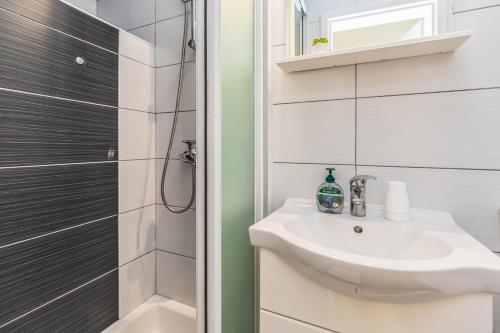 a white bathroom with a sink and a shower at Apartment Adrian in Baška Voda
