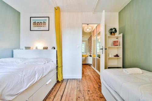 1 dormitorio con 2 camas blancas y suelo de madera en Lille The apartment in the trees, en Lille