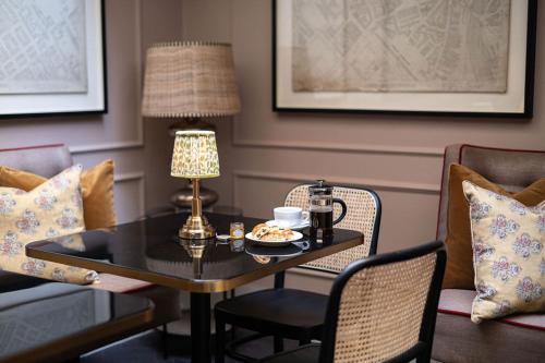 a table with a cup of coffee and a lamp on it at The Tophams Hotel in London