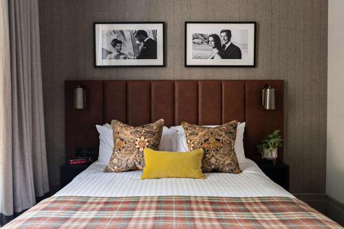 una camera con un letto con tre immagini appese al muro di The Tophams Hotel a Londra