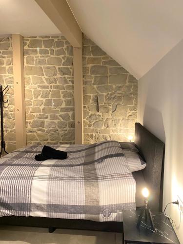 una camera con letto e parete in pietra di Ciney - Le nid du Clocher a Ciney