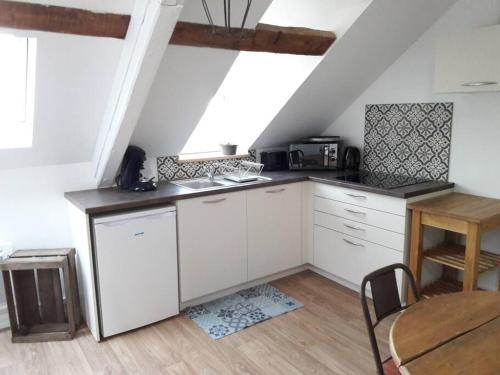 - une cuisine mansardée avec des placards blancs, une table et des chaises dans l'établissement Appartement familiale jusqu'à 4 personnes 5mn à pied du centre, à Honfleur