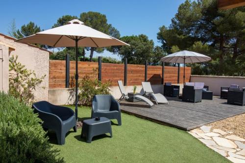 a patio with chairs and an umbrella and a table at La Grande Auguière, villa familiale et spacieuse au cœur du vignoble et à 300m de la mer in Hyères