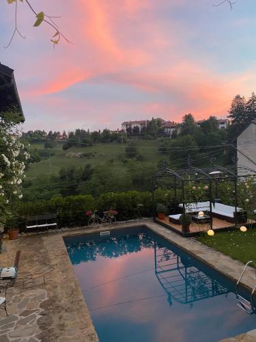 a swimming pool with a sunset in the background at Maison Otto in Bossolasco