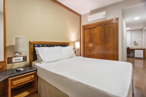 a bedroom with a large white bed with a wooden headboard at Bourbon Londrina Hotel in Londrina