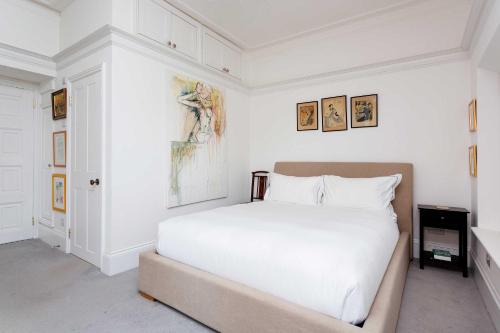 a bedroom with a white bed and paintings on the wall at Veeve - Richmond on Canvas in Richmond upon Thames