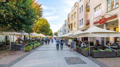 a group of people walking down a street with tables and umbrellas at Comfy Apartments - Lux Na Fali - Monte Cassino in Sopot