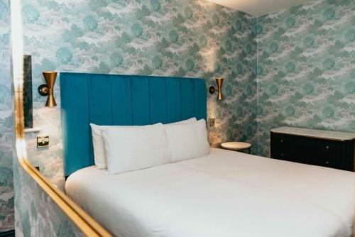 a bed with a blue headboard in a room with wallpaper at Lock and Key Boutique Hotel - Duke Street in Liverpool