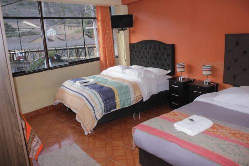 Habitación de hotel con 2 camas y ventana en hostal Qorisonqo inn ollantaytambo en Ollantaytambo