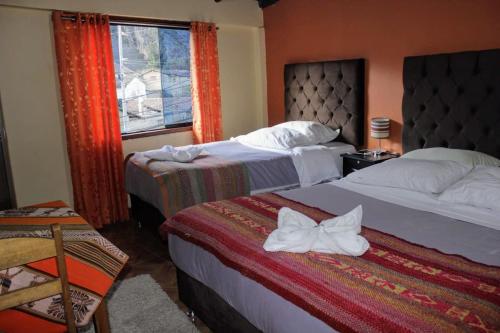 Habitación de hotel con 2 camas y ventana en hostal Qorisonqo inn ollantaytambo, en Ollantaytambo