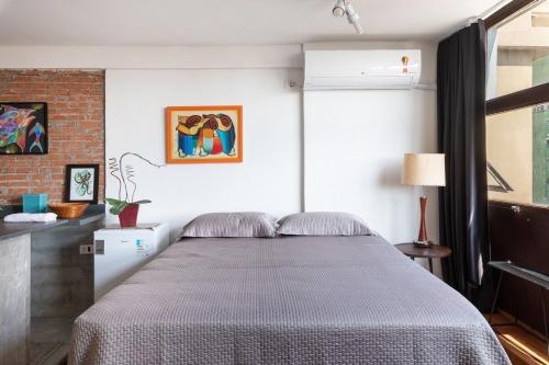 1 dormitorio con cama y pared de ladrillo en Loft do Serjoca, en São Paulo