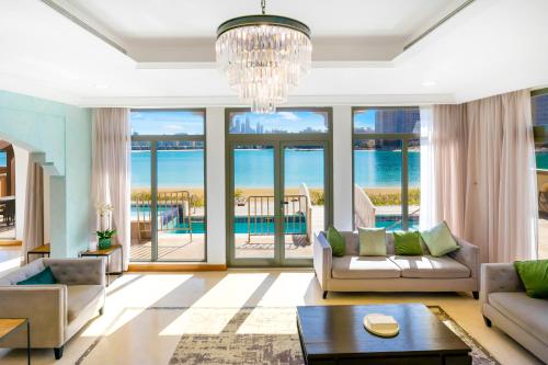 a living room with a couch and a chandelier at FAM Living - Palm Jumeirah - Beach Villas with Private Pool in Dubai