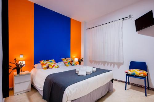 a bedroom with a blue and orange wall at Anfitrión Sevilla 6 in Seville