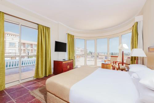 pokój hotelowy z łóżkiem i dużym oknem w obiekcie Coral Sea Beach and Aqua Park w mieście Ajn Suchna