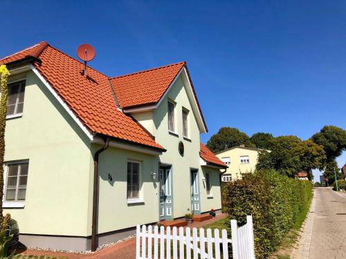Casa blanca con techo naranja y valla blanca en Am Meer Backbord, en Wustrow