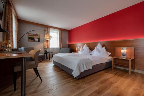 a hotel room with a bed and a red wall at Biobausewein WEIN HOTEL LEBEN in Iphofen