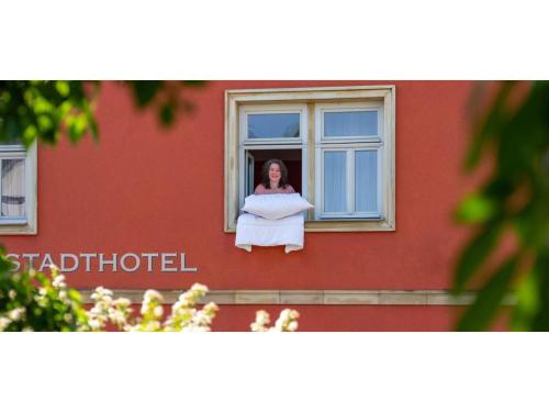 Una mujer está mirando por una ventana en Biobausewein WEIN HOTEL LEBEN en Iphofen