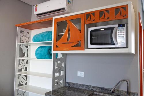 a kitchen with a microwave above a sink at Pousada Guaricana in Pontal do Paraná