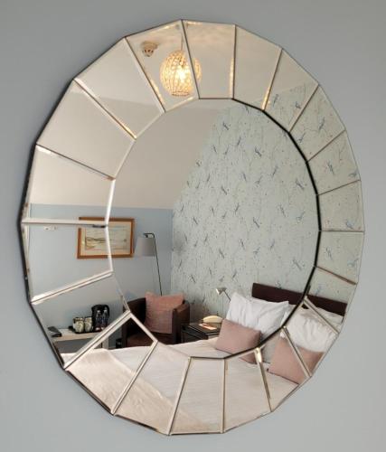 a mirror reflecting a room with a couch and a chair at Loch Melfort Hotel in Ardfern