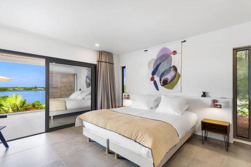 a bedroom with a large bed and a large window at Slowlife Wellness Villa! in Baie Longue