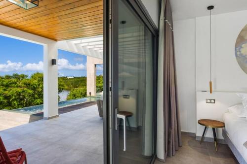 a bedroom with a view of a bed and a balcony at Slowlife Wellness Villa! in Baie Longue