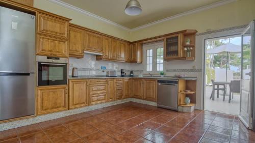 a kitchen with wooden cabinets and stainless steel appliances at 8-Bed Villa in Vilamoura-Sleeps-Playground-Pool in Vilamoura