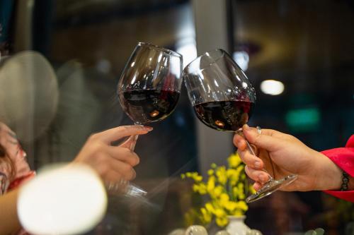 two people holding up glasses of red wine at Nostalgia Halong Cruise in Ha Long