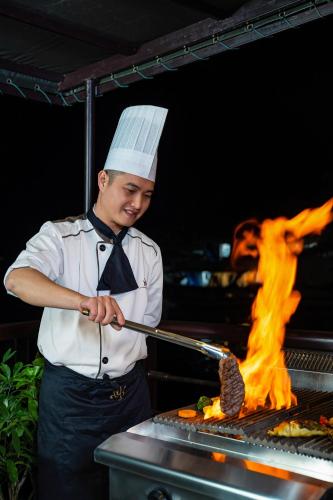 a chef is cooking food on a grill at Nostalgia Halong Cruise in Ha Long