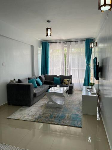 a living room with a couch and a table at Zoe Homes Country Cottages 1bedroom Green square in Kericho