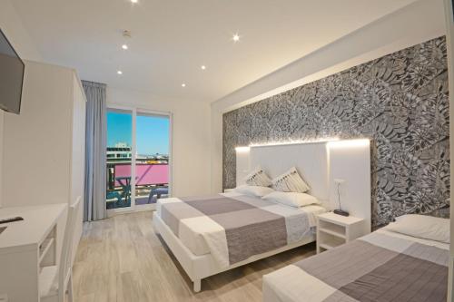 a bedroom with two beds and a large window at Hotel Kent in Riccione