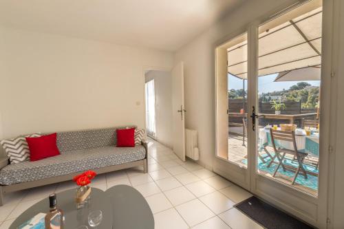 a living room with a couch and a view of a pool at Le Verger, villa lumineuse et agréable avec son espace extérieur clos au cœur de notre vignoble in Hyères