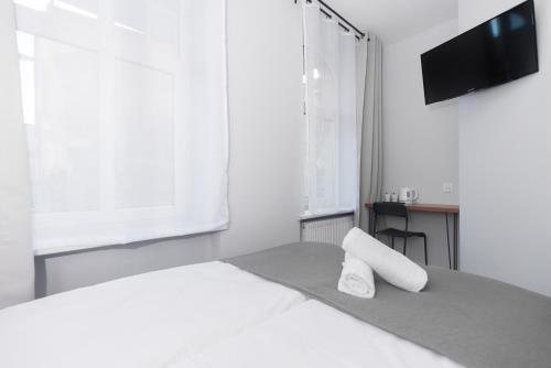 a white bedroom with a bed and a flat screen tv at Zefiro Seredyńskiego in Gdańsk