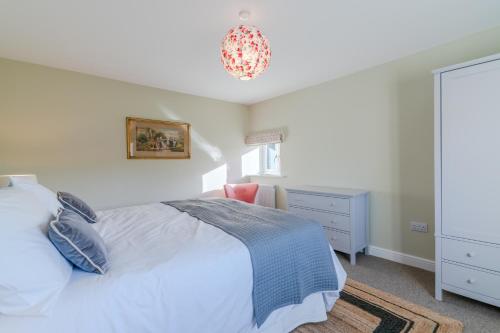 a bedroom with a bed and a dresser and a chandelier at Quarry Lodge in Lydney