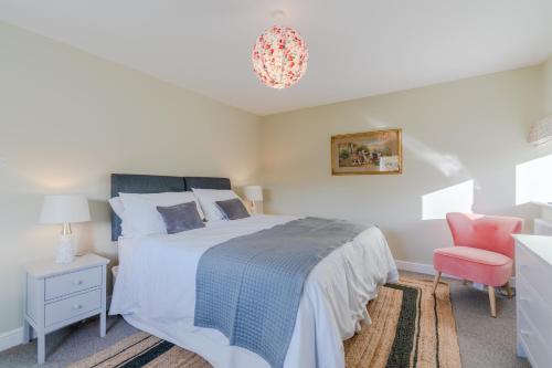 a bedroom with a bed and a pink chair at Quarry Lodge in Lydney