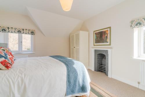 a white bedroom with a bed and a fireplace at Quarry Lodge in Lydney